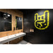 Modern bathroom with white trough sink, stainless steel faucets, black pendant lights, and yellow graphic on black wall.