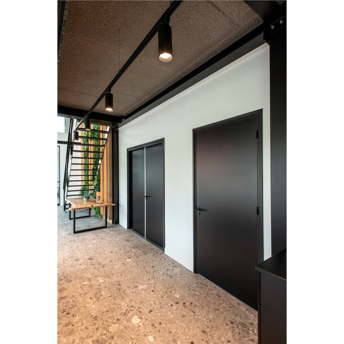 Interior view with black doors, track lighting, wood table, and terrazzo flooring.