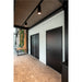 Interior view with black doors, track lighting, wood table, and terrazzo flooring.
