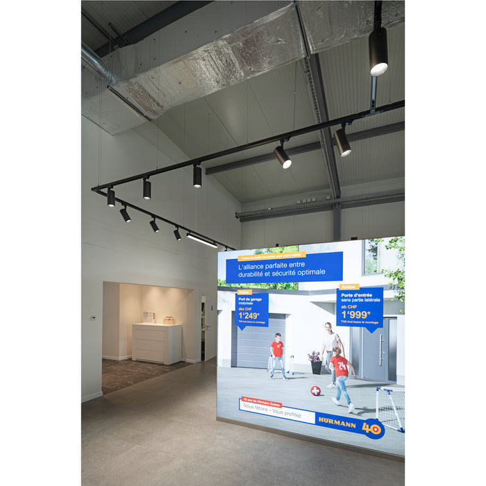 Modern black track lighting with cylindrical spotlights, ceiling mounted.