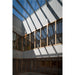 Interior atrium with glass skylight, wood frame windows, and perforated white metal panels.
