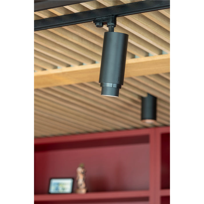Black track lighting fixture, cylinder shape, mounted on ceiling track.