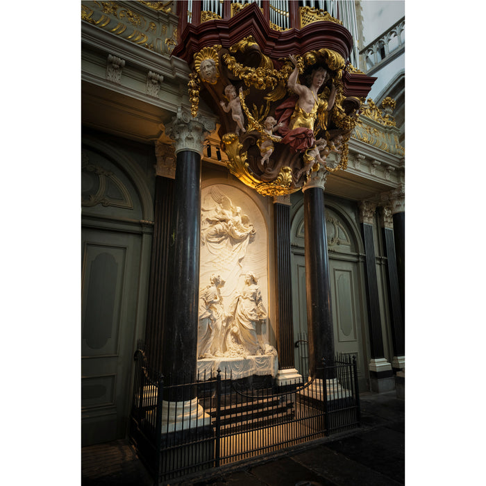 Ornate church interior featuring a white marble relief sculpture and gilded wood carvings.