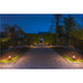 Bronze finish path lights illuminating a gravel walkway through a formal garden at dusk.