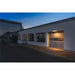 Gray steel sectional garage door with windows on a white building.