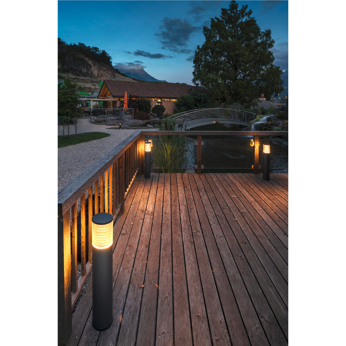 Black bollard light fixture on wood deck, outdoor landscape lighting.