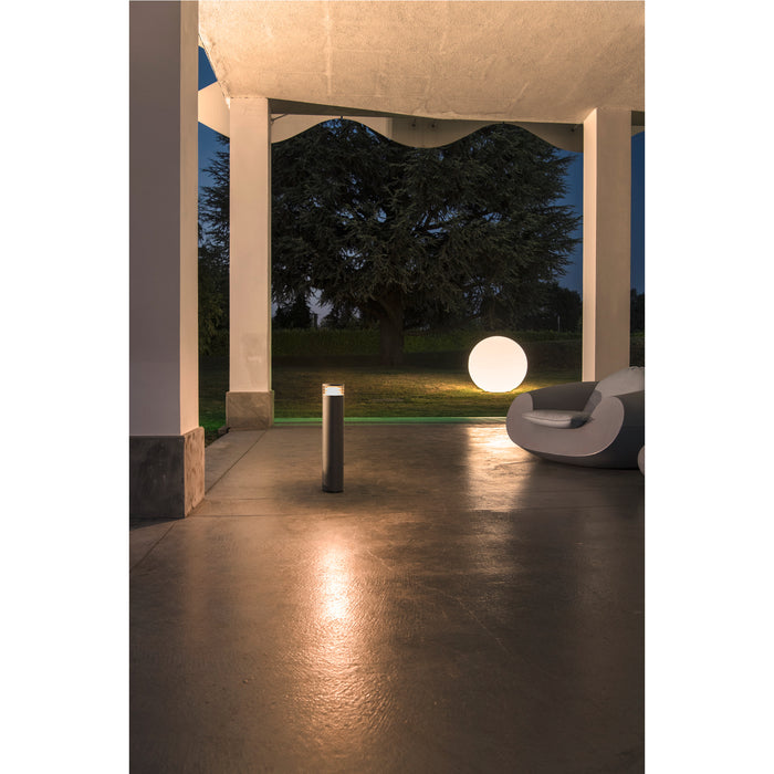 Modern gray bollard light fixture, ground mounted.