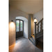 Interior hallway with brick floor, gray painted stairs, black door, and black wall-mounted cylinder sconces.