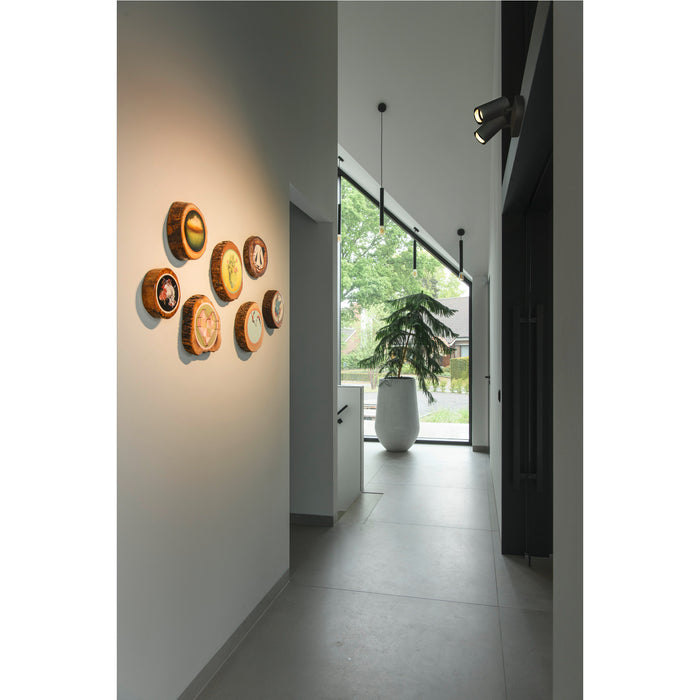 Wall-mounted wood slice art with colorful painted designs, in a modern hallway.