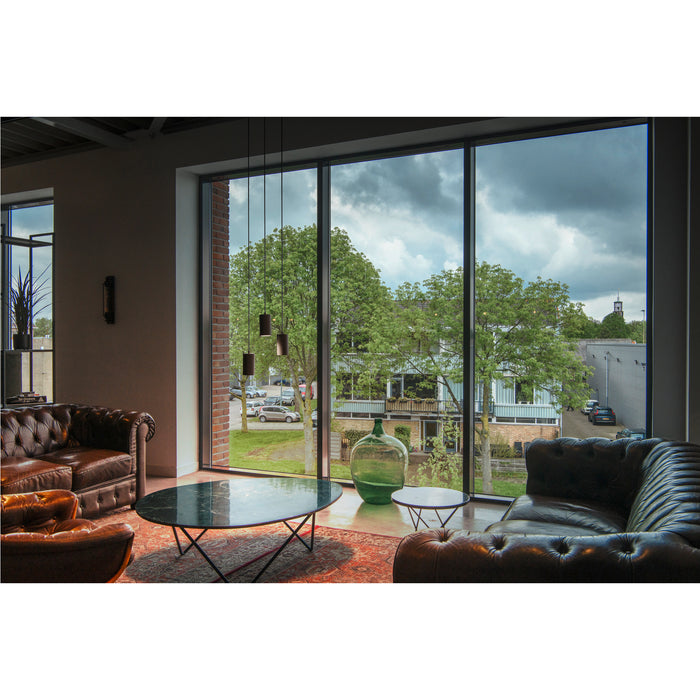 Living room with brown leather Chesterfield sofas, black metal frame tables with green marble tops, and large windows.