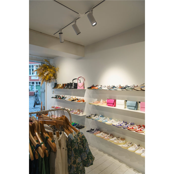 Boutique interior with clothing rack, shelves of shoes and handbags in various colors.