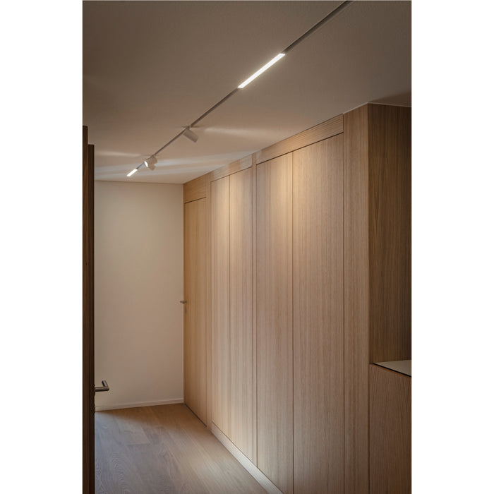Modern hallway with light wood cabinets, track lighting with white spotlights, and light wood flooring.