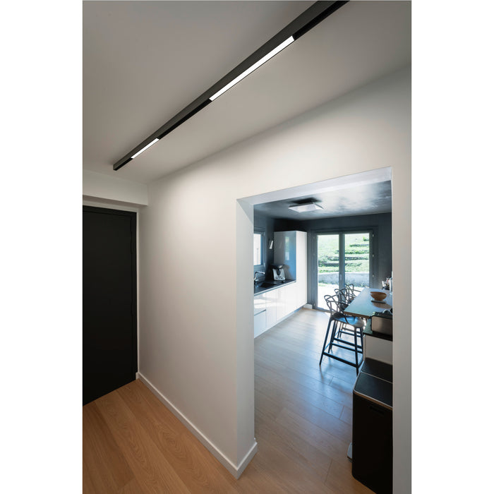 Black linear LED ceiling light fixture in modern hallway.
