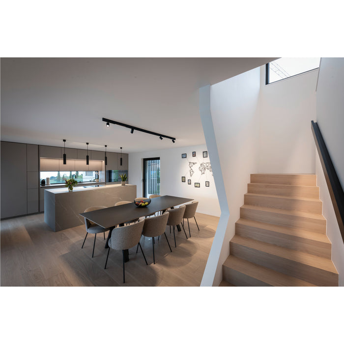 Modern kitchen and dining area with gray cabinets, dark table, upholstered chairs, and light wood stairs.