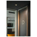 Gray door with silver trim and letter "D", flush-mounted ceiling light.