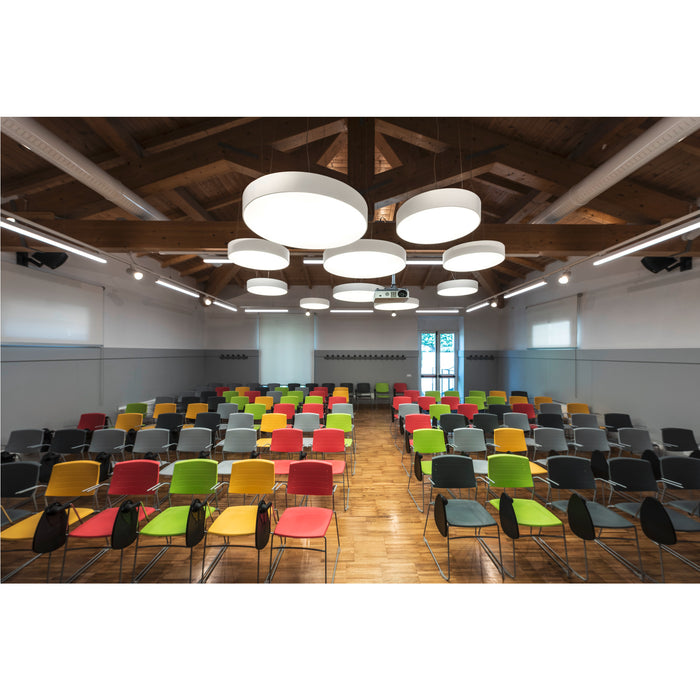 Auditorium with rows of colorful plastic chairs (red, green, yellow, gray, black) on a wood floor.