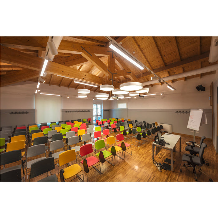 Conference room with colorful plastic chairs (red, yellow, green, gray, black) on metal frames, wood floor and ceiling.