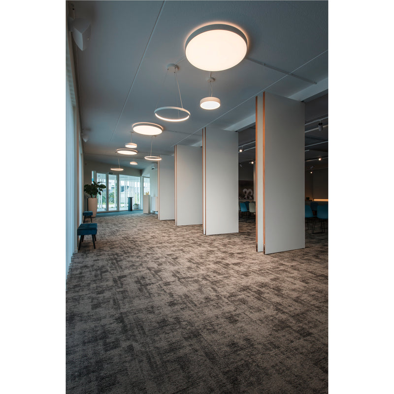 Modern office hallway with gray patterned carpet, white movable walls with wood trim, and round LED ceiling lights.