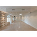 Empty event space with terrazzo floor, stone accent wall, white walls, and ceiling-mounted lighting.