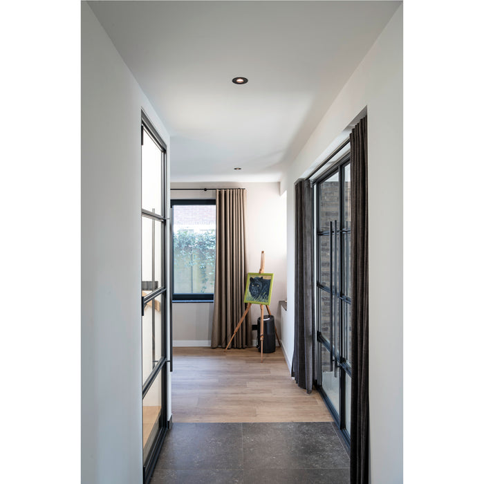 Hallway with black metal frame doors, gray curtains, wood floors, and dark stone tile.