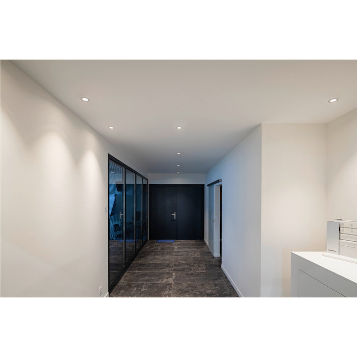 Hallway with recessed white ceiling lights, black framed glass wall, and dark tile floor.