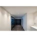 Hallway with recessed white ceiling lights, black framed glass wall, and dark tile floor.