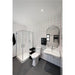 Modern bathroom with white tile, red grout, wall-mounted sink, oval mirror, glass shower, and gray speckled flooring.
