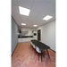 Modern office kitchen with black table, white chairs, and pink herringbone floor.