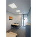 Office interior with recessed square LED ceiling lights, a wood table with metal legs, and black chairs.