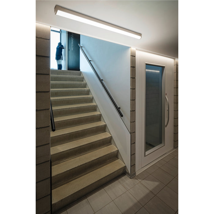 Concrete stairs with black metal handrail, white walls, and recessed linear lighting.