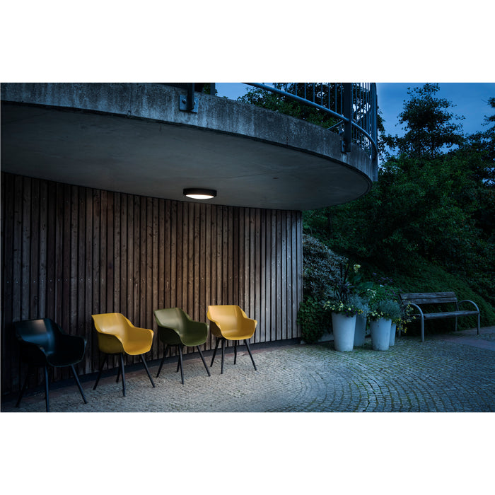 Modern outdoor scene with black, yellow, and green plastic chairs with black legs.