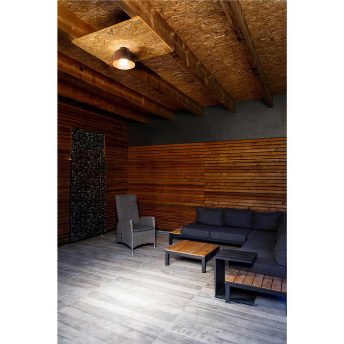 Outdoor patio with gray wicker chair, dark gray sofa, wood and metal tables, and ceiling-mounted bronze light fixture.
