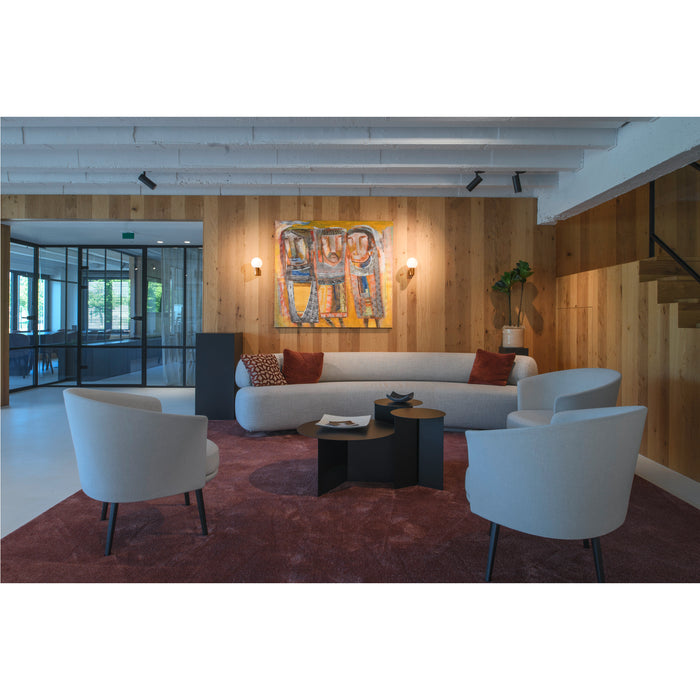 Modern living room with light gray fabric sofa and chairs, black metal tables, and a burgundy rug.