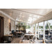 Restaurant interior with wood tables, gray upholstered chairs, stone wall, and white track lighting.