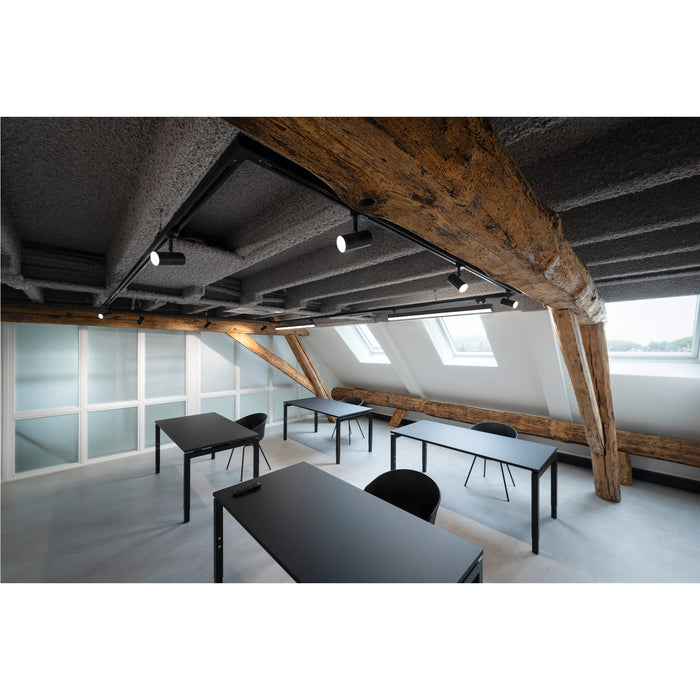 Modern office space with black metal frame tables and chairs, track lighting, and exposed wood beams.