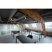Modern office space with black metal frame tables and chairs, track lighting, and exposed wood beams.