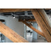 Black track lighting with cylindrical heads, surface mounted on a wood beam ceiling.
