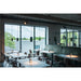 Restaurant interior with metal chairs, dark tables, green banquette seating, and black pendant lights.