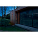Black wall-mounted outdoor light fixture on wood siding of modern building.
