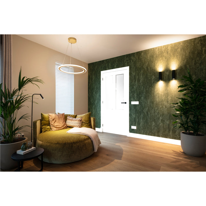 Living room interior with green velvet round sofa, white door, and modern lighting fixtures.