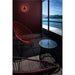 Outdoor patio with red string chairs, glass-top table, and round black wall-mounted light fixture.