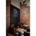 Interior with brown leather armchairs, wood tables, brick wall, and gold metal ring pendant light.