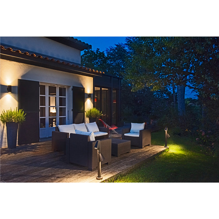 Outdoor patio with dark brown wicker furniture, white cushions, and black metal post lights.