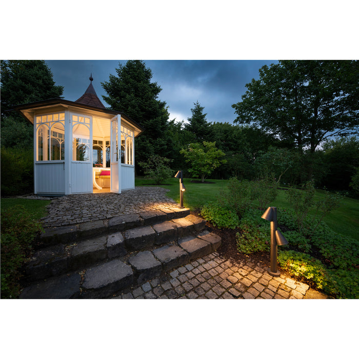 White wooden gazebo with copper roof, stone steps, and dark bronze finish path lights illuminating a garden.