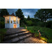 White wooden gazebo with copper roof, stone steps, and dark bronze finish path lights illuminating a garden.
