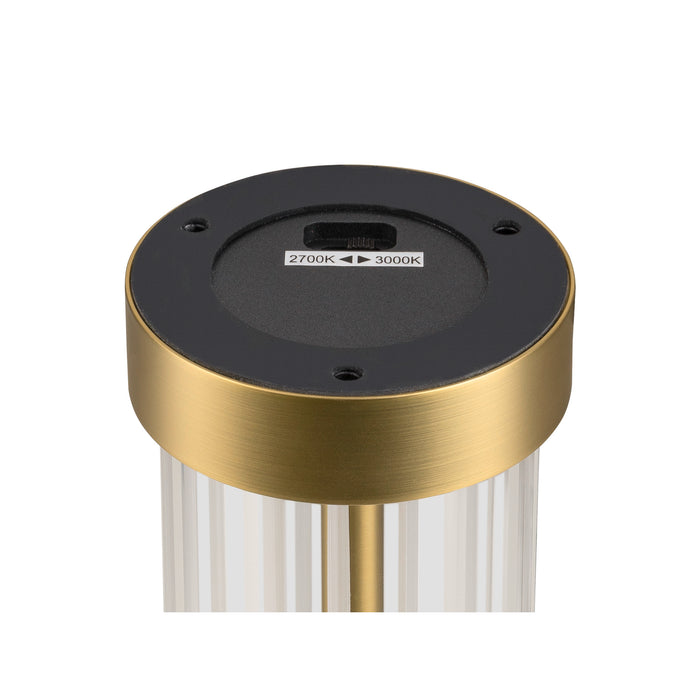 Close-up of a table lamp base showing the 2700K-3000K color temperature switch, gold finish, and fluted glass.