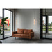 Brown faux leather sofa with black metal legs, and two hanging glass and metal pendant lights.