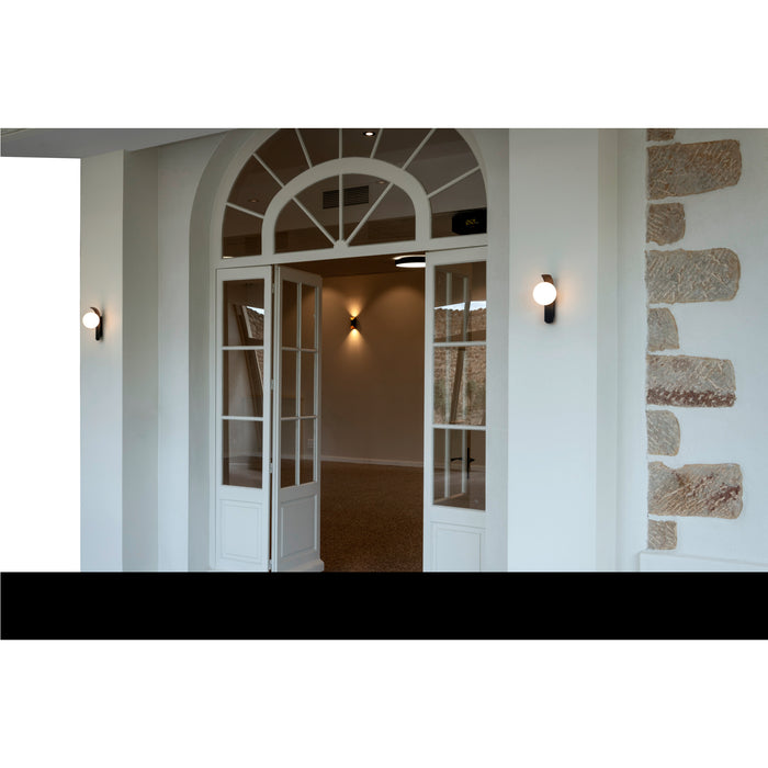 White arched French doors with glass panes, opening to a room with sconces and stone wall accents.