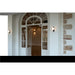 White arched French doors with glass panes, opening to a room with sconces and stone wall accents.
