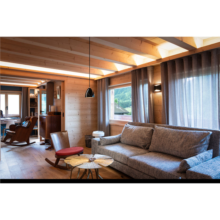 Living room with gray textured fabric sofa, wood walls, and black pendant light.